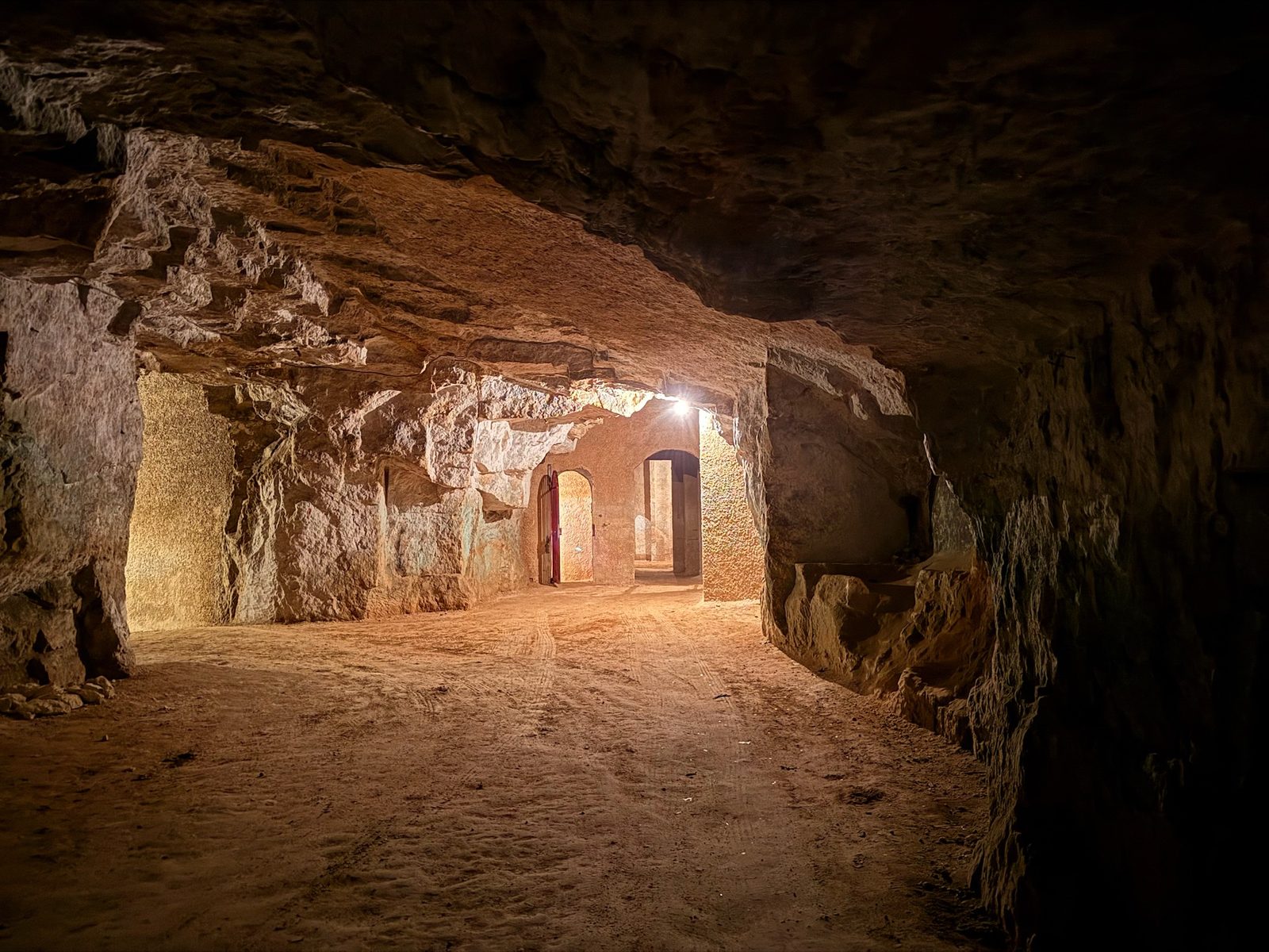 Inside a tuffeau cellar, bottles resting against the pale limestone